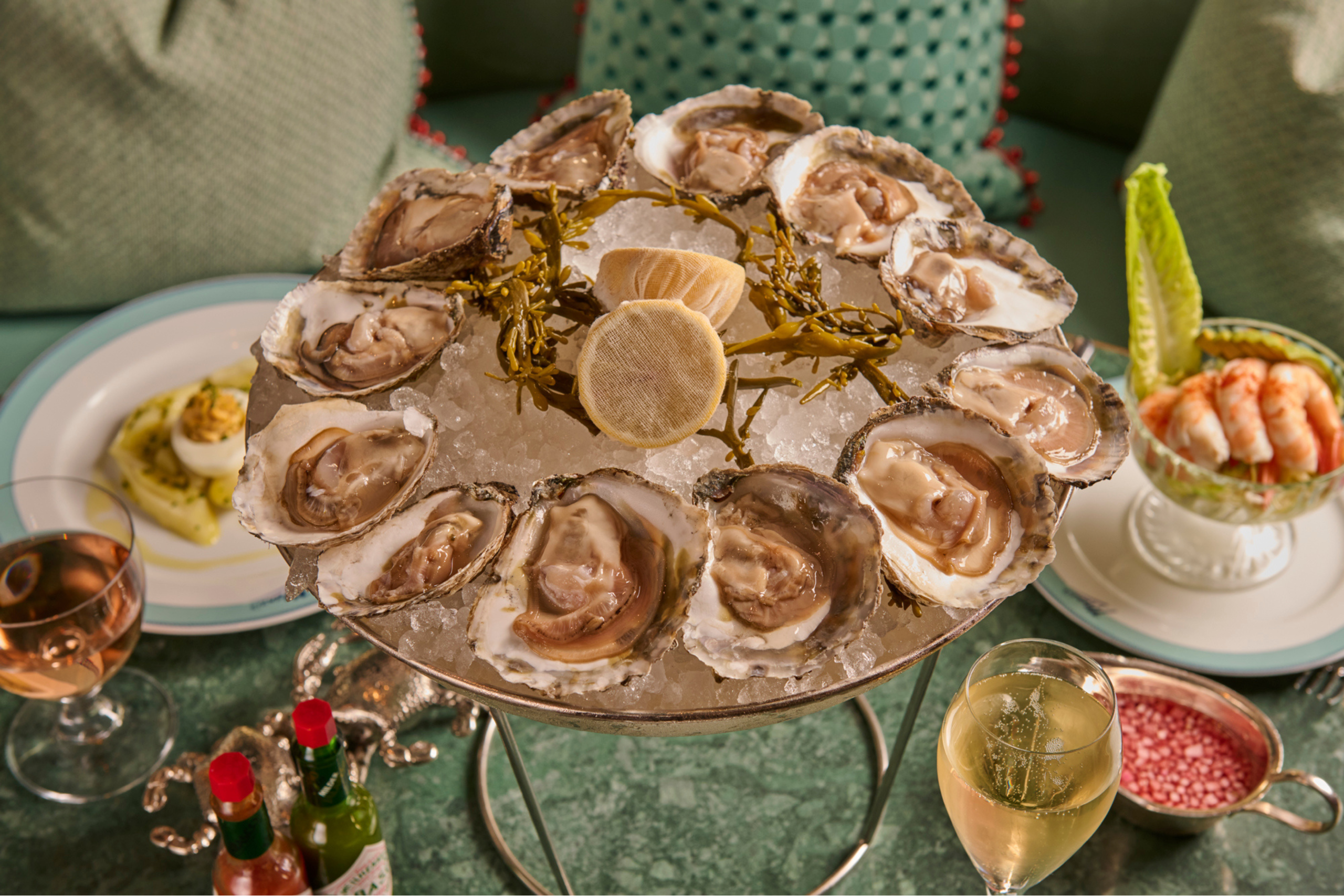 Raw oysters on an elevated silver dish, filled to the brim with ice, fresh lemon